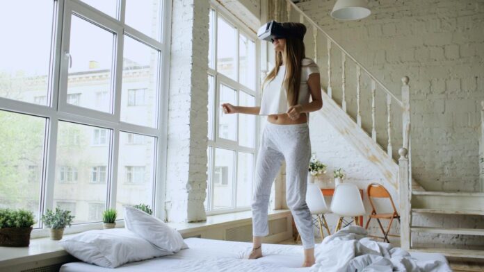 Woman wearing vr headset standing on bed
