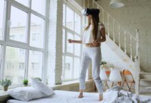 Woman wearing vr headset standing on bed